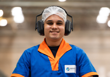 imagem de um colaborador com uniforme da Ibratec, touca na cabeça e fone protetor de audição